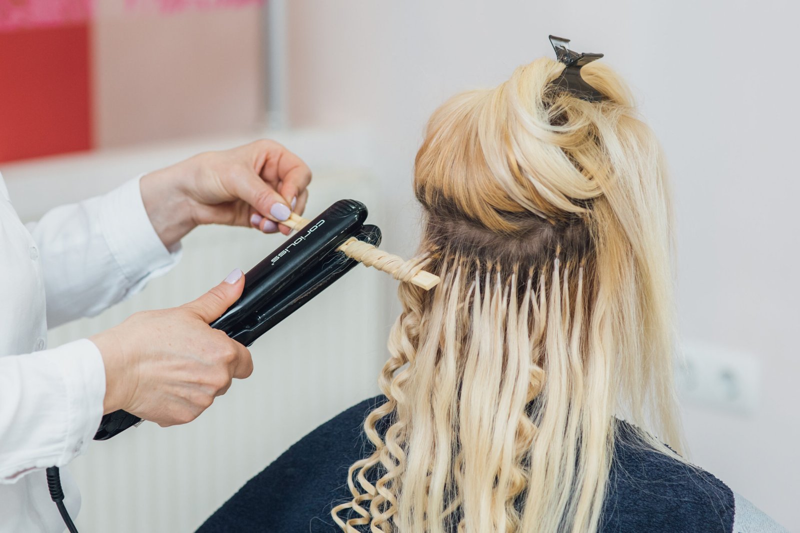 Hairdresser makes hairstyle close-up on blond hair of beautiful woman